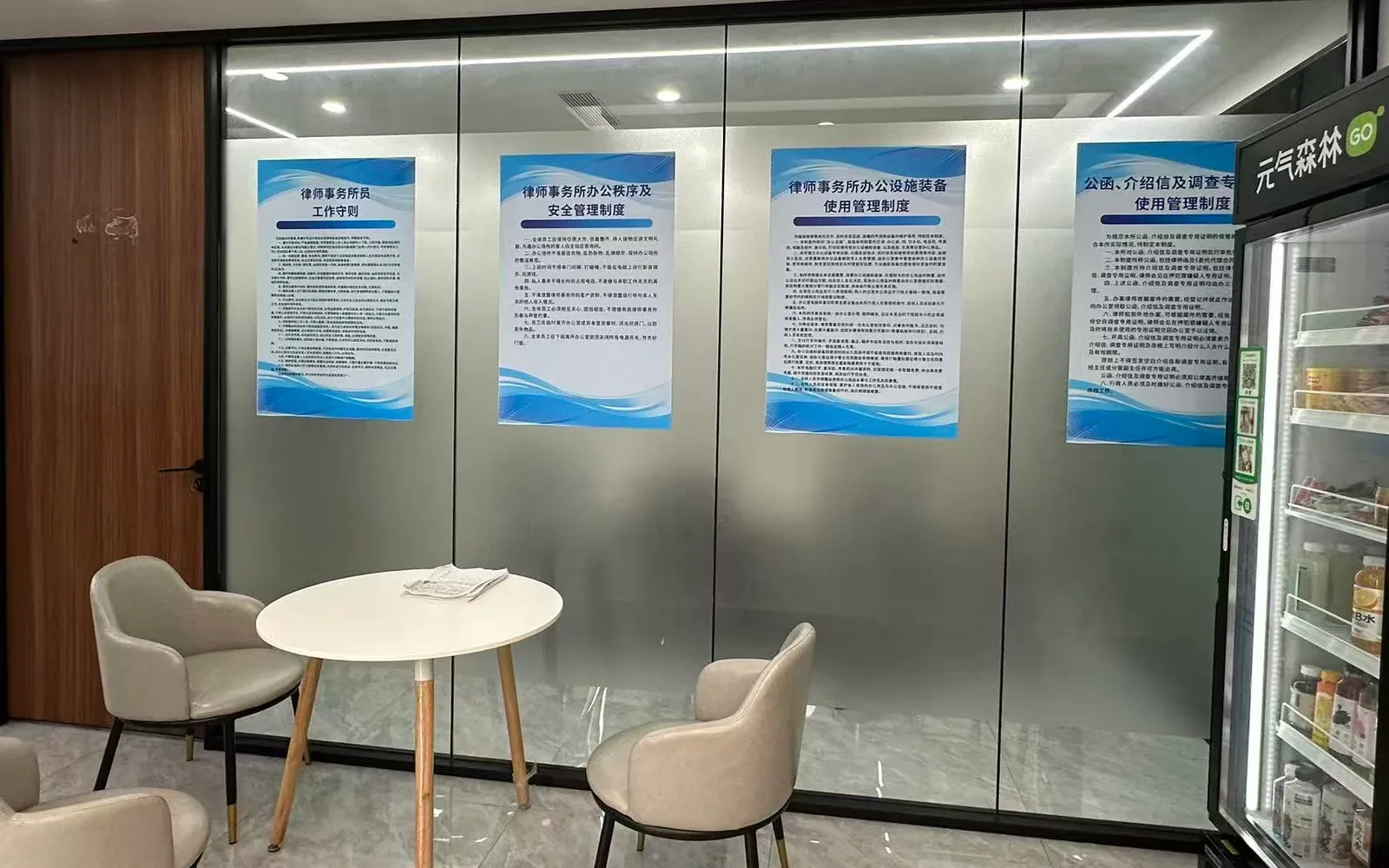 Meeting corner with a round table; the firm’s internal rules posted on the glass wall